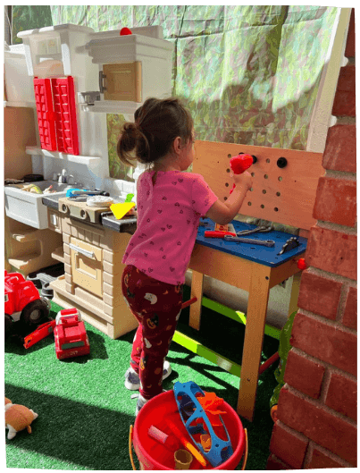 Child playing with hammer and pegboard outdoors at Mama Bear Daycare, daycare in Lake Forest.