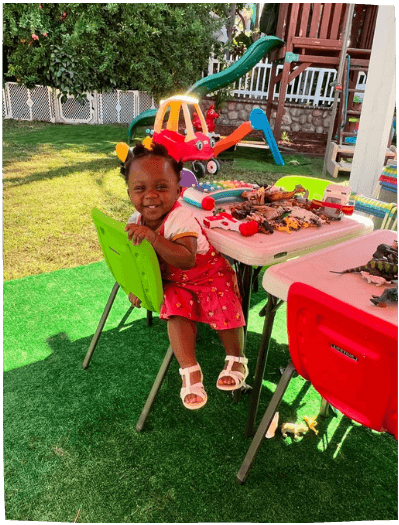 Toddler girl playing outdoors at table with toys at Mama Bear Daycare, daycare in Lake Forest.